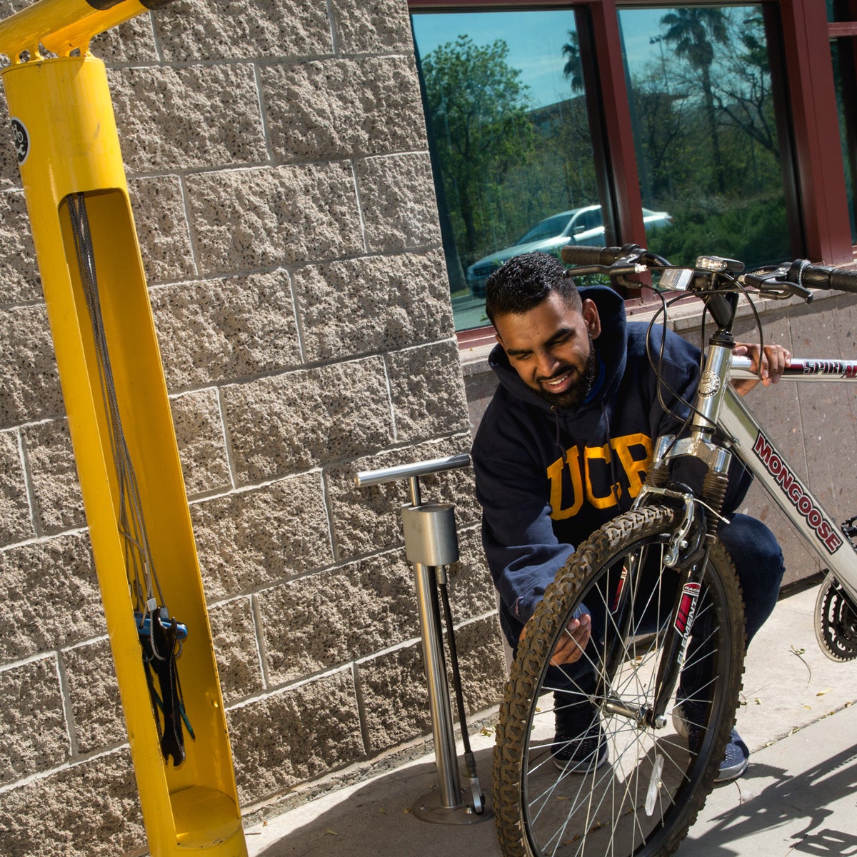 Male student fills the tires on his bicycle from an air station on campus.