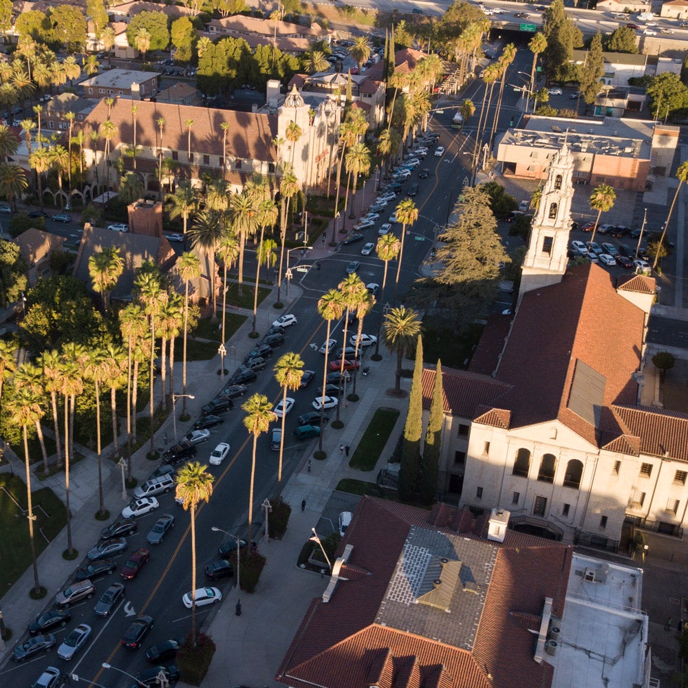 Aerial view of Downtown Riverside that shows historic buildings, tall palm trees and car-lined street.