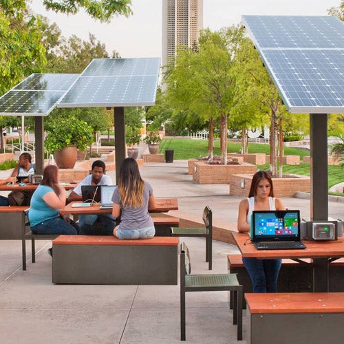Small groups of UCR students sit at solar panel tables to meet up with friends, eat, study, and charge their devices.