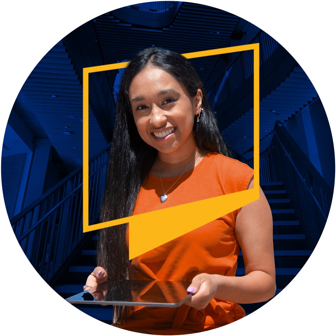 A female student is standing at the foot of the stairway at the Student Success Center holding a tablet. The essence of the UCR logo is framing her head and shoulders.