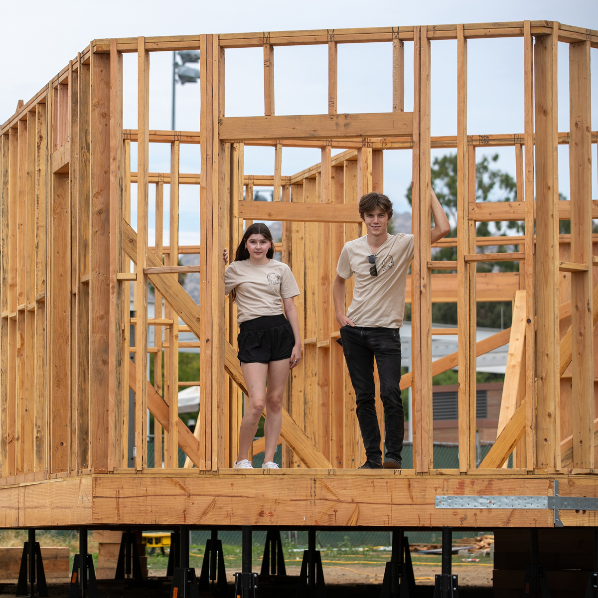 Team members Chloe Russ and Cooper Proulx stand inside the frame of the under-construction home, their team’s entry in the 2023 Orange County Sustainability Decathlon to envision the future of sustainable housing in California