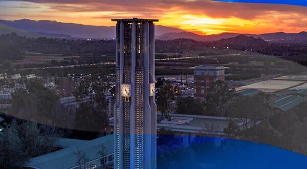 Aerial view of the Bell Tower on the UCR campus. The sun is setting behind the mountains in the background giving off a bright orange light.