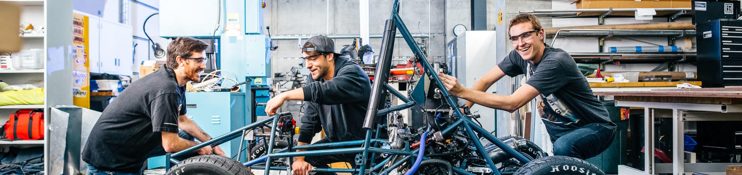 Three male students work on a go-cart project in a lab at the Marlan and Rosemary Bourns College of Engineering