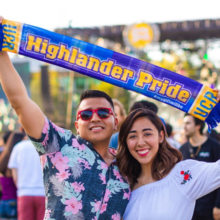 Male and female UC Riverside students waving around a "Highlander Pride" scarf above their heads.