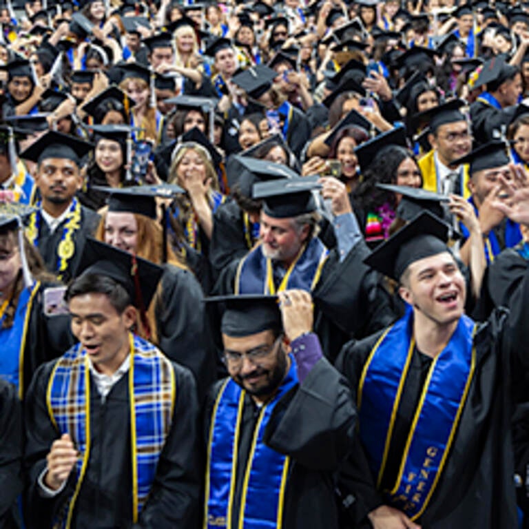 Students in caps and gowns move their tassels as part of the commencement ceremony