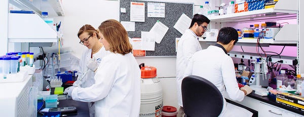 Two women in lab coats perform an experiment in a lab