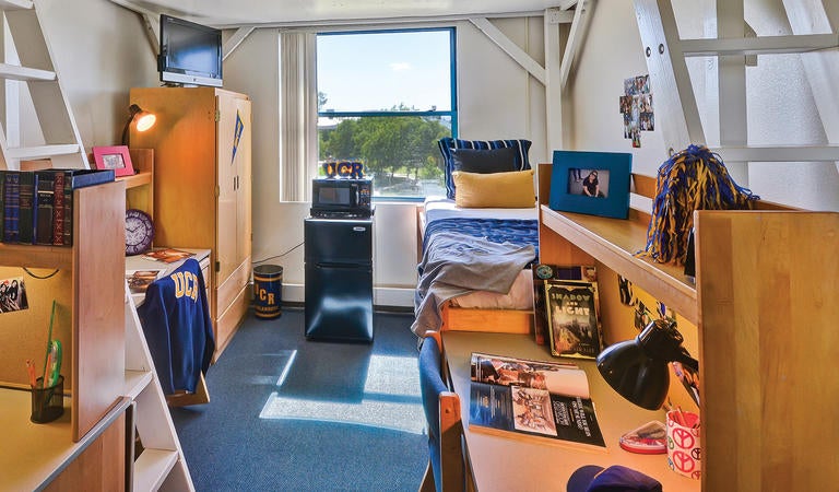 A decorated dorm room. Stairs to one side suggest it is a loft style room. 