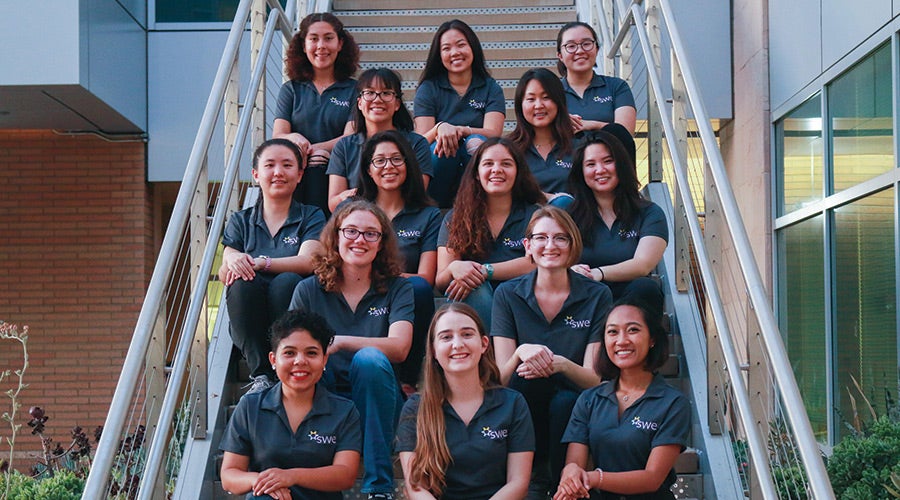 The members of UCR's Society of Women Engineers pose sitting on a staircase