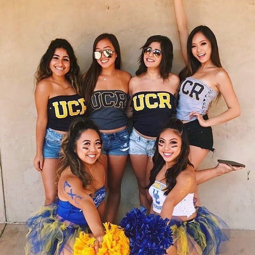 Six UCR students wearing UCR tube top shirts, while holding cheerleading pom poms.