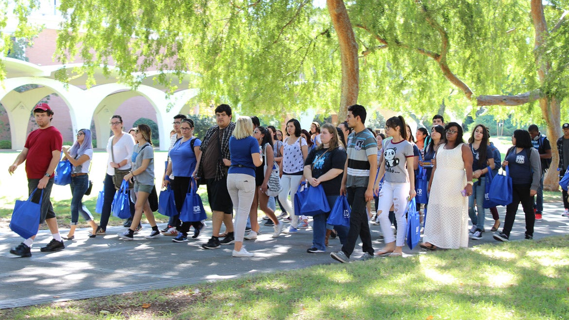 A UCR student leads a group past the Rivera Library on a campus tour