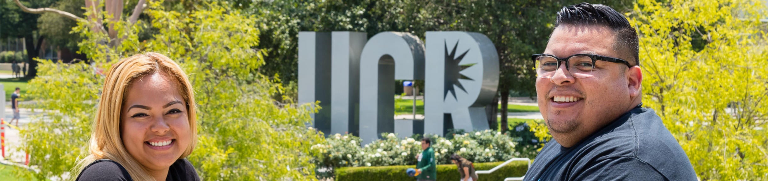 Two veteran students sit in front of the UCR sign